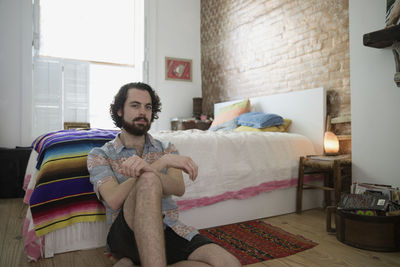 Young man sitting beside his bed