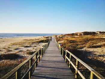 Boardwalk at beach against clear sky