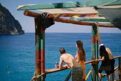 Rear view of people on sea against sky