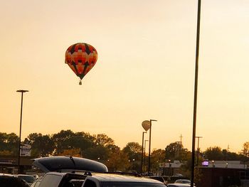 Hot air balloon flying over trees against sky during sunset