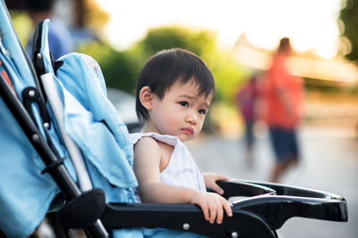 Baby looking away while sitting in carriage outdoors