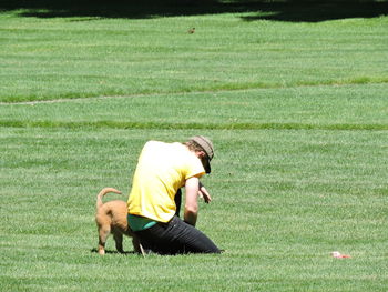 Rear view of man holding dog on field