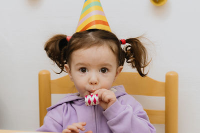 Portrait of a beautiful girl blowing a trumpet at a birthday party.