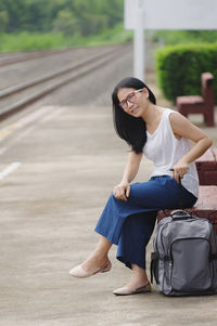 Portrait of woman with backpack sitting on railroad station platform