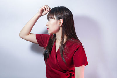 Young woman looking away while standing against white background