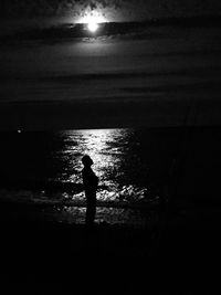 Silhouette man standing on beach against sky at sunset