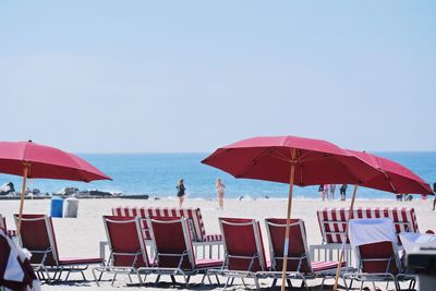 Lounge chairs on beach against clear sky