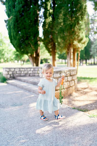 Full length portrait of cute baby girl sitting on tree