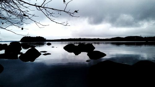 Silhouette men on lake against sky