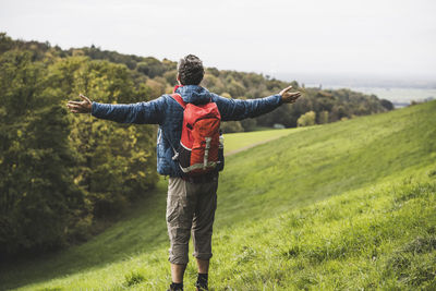 Carefree man with arms outstretched standing under sky