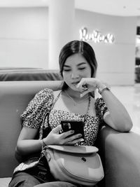 Portrait of young woman sitting on sofa at home