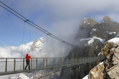 Rear view of people walking on snow covered mountain against sky