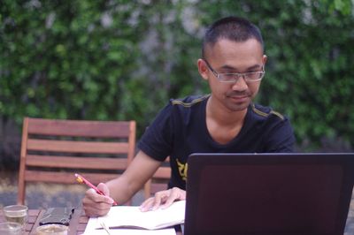 Man using laptop while sitting outdoors