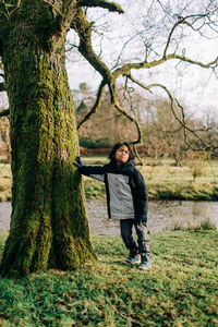 Portrait of smiling young man standing on tree trunk