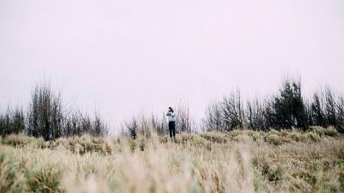 Person photographing on field against clear sky