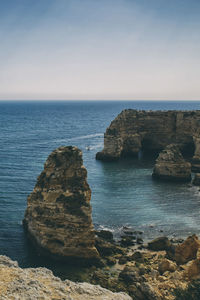 Scenic view of rocks in sea against clear sky