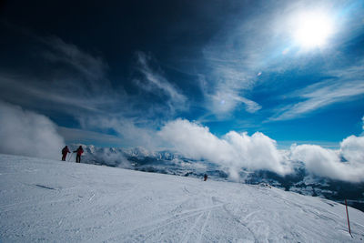 People skiing on snowcapped mountain against sky