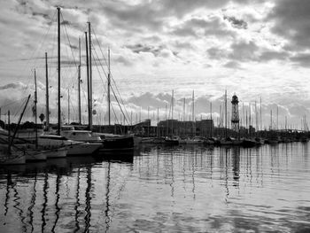Sailboats moored on harbor in city against sky