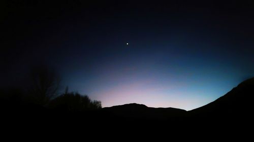 Low angle view of silhouette mountain against sky at night