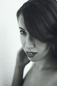 Close-up of smiling young woman against wall