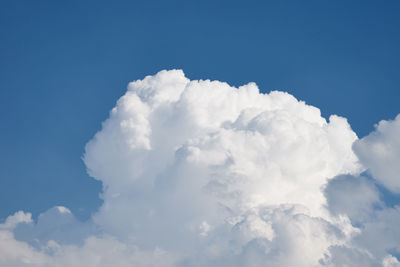 Close up of big white fluffy cloud on clear blue sky