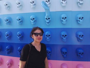 Portrait of woman in sunglasses standing against wall