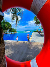 People swimming in pool by sea against sky