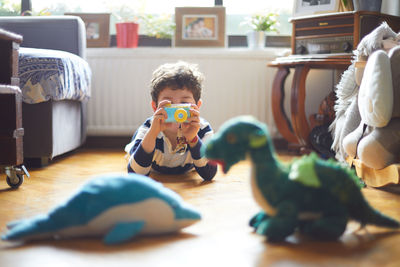 A boy takes photos of his toys with his camera