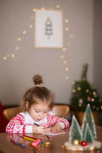 Girl in illuminated christmas tree at home