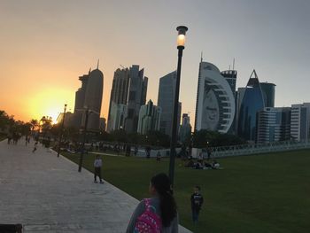 People on modern buildings in city during sunset