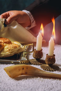 Cropped hand of man holding napkin with bread and candles on table