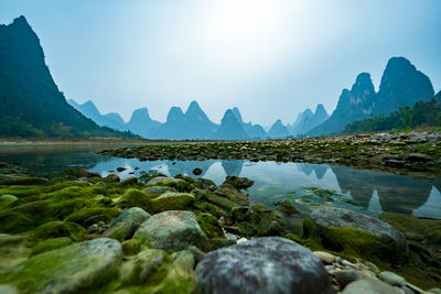 Rocks by lake against sky
