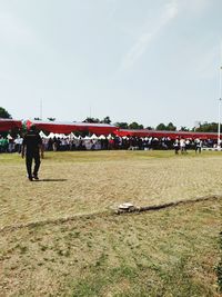 People walking on field against sky