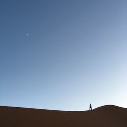 Man standing on desert against clear blue sky