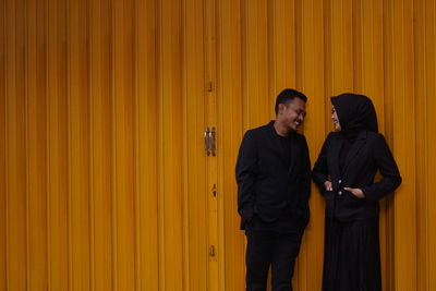 Young man standing against yellow wall