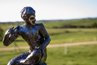 Close-up of statue on field against sky