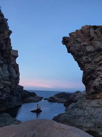 Rock formations by sea against blue sky