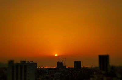 Silhouette buildings against romantic sky at sunset