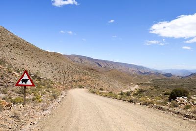 Road by mountains against sky