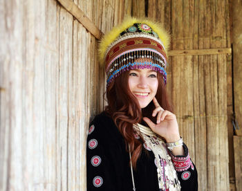 Smiling woman in traditional clothing looking away by wall