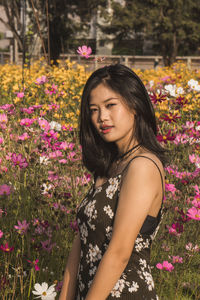 Portrait of woman standing by blooming flowers