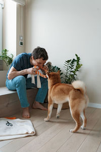 Funny adult man playing with a homemade dog toy with his favorite furry dog friend