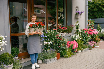 Portrait of young woman standing by flowers