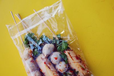 High angle view of food in plastic packet against yellow background