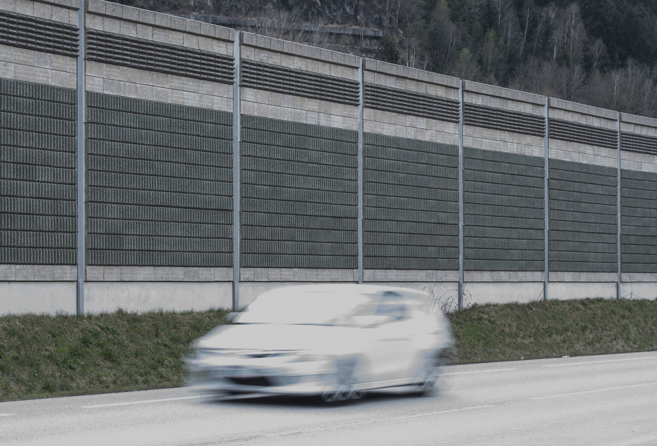 BLURRED MOTION OF CAR ON ROAD AGAINST BUILDING