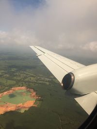 Aerial view of airplane wing over landscape against sky