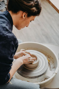 A woman in a pottery workshop works on a potter's wheel