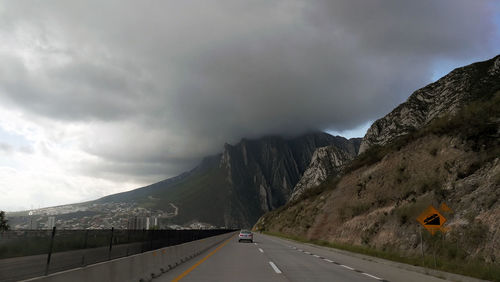 Road by mountains against sky