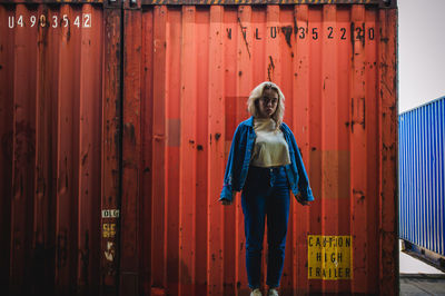 Portrait of woman standing against cargo container