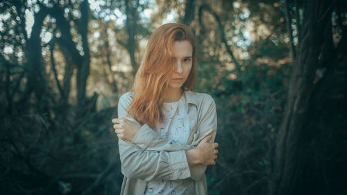 Young woman standing against trees